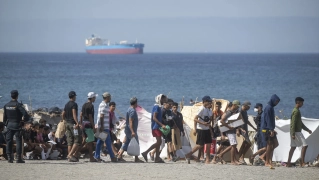 Decenas de migrantes caminan por la playa del Trampolín, en Ceuta. Marcos Moreno / Europa Press