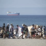 Decenas de migrantes caminan por la playa del Trampolín, en Ceuta. Marcos Moreno / Europa Press