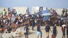 Decenas de migrantes en la playa de El Trampolín, Ceuta, este lunes. Marcos Moreno / Europa Press
