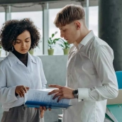 Dos colegas de negocios examinando documentos | Pexels/Mikhail Nilov