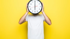 handsome man white t shirt transperent glasses hold big clock place his head