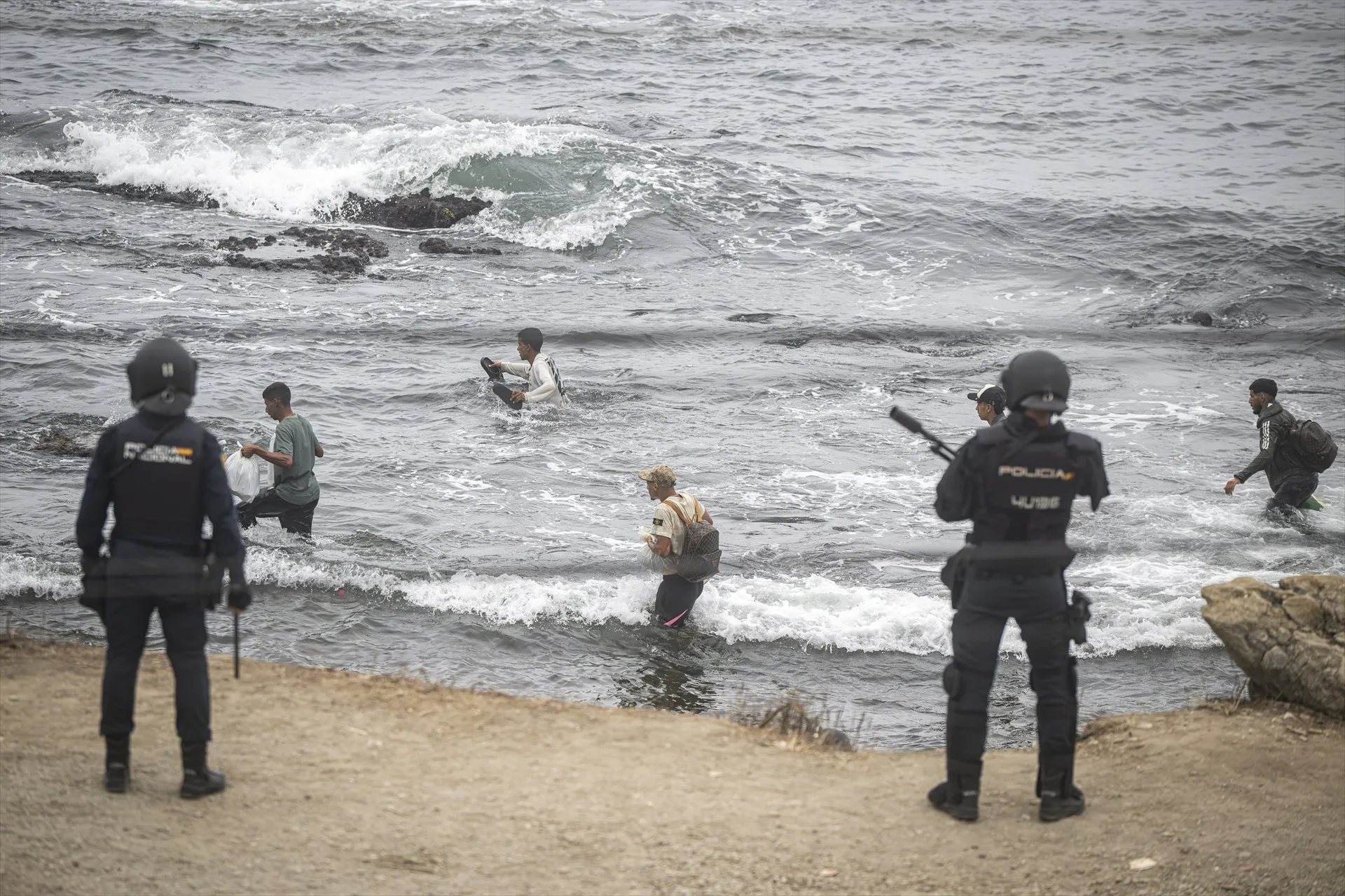 Agentes de la Policía Nacional intervienen durante el proceso de desalojo del embolsamiento de migrantes en la playa de El Trampolín. Fuente: Marcos Moreno / Europa Press.