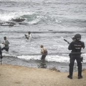 Agentes de la Policía Nacional intervienen durante el proceso de desalojo del embolsamiento de migrantes en la playa de El Trampolín. Fuente: Marcos Moreno / Europa Press.