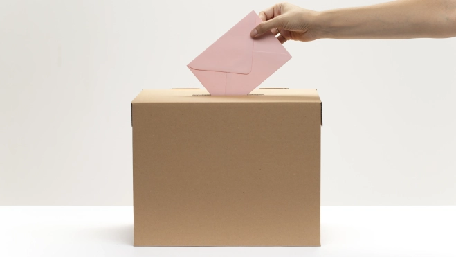 La mano pone el sobre rosado en la casilla de votación. Fuente: Magnific. La mano pone el sobre rosado en la casilla de votación. Fuente: Magnific.
