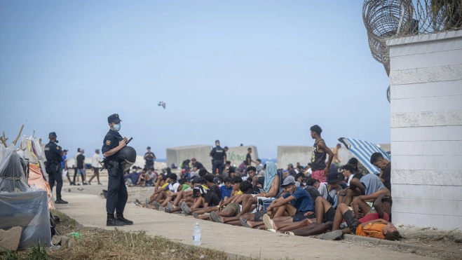 Varios agentes de Policía Nacional controlan a los migrantes en la playa del Trampolín. Fuente: Marcos Moreno / Europa Press.