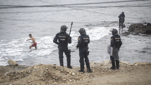 Agentes de la Policía Nacional intervienen durante el proceso de desalojo del embolsamiento de migrantes en la playa de El Trampolín. Marcos Moreno / Europa Press