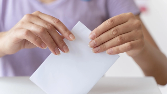 Persona colocando su voto en una casilla. Fuente: Magnific.