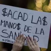 Un manifestante sujeta un cartel durante una concentración ante el Hospital de Torrejón,